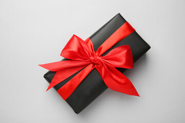 Gift box with red bow on light grey background, top view