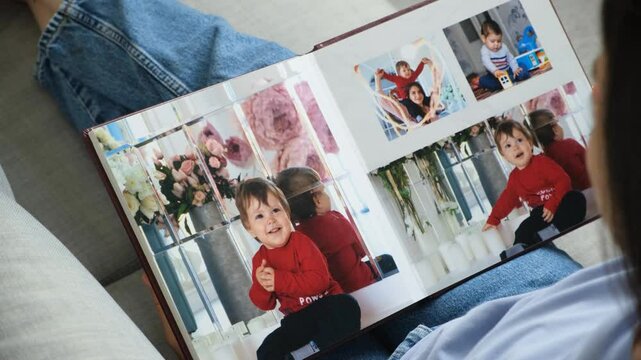 Opening photo book in the hands of a woman, home family photo album.