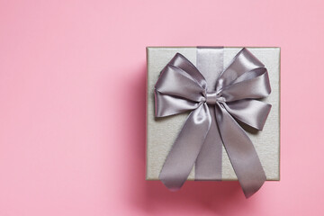 Gift box with bow on dusty pink background, top view