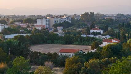 View of the city of Perpignan, France, sunset, haze, red roofs, houses, trees, life, vacation, postcard, Europe, mountain silhouettes, calm, beauty