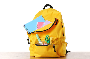 Naklejka premium Backpack with different school stationery on wooden table against white background