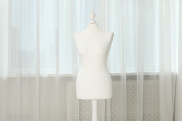 One female mannequin on stand near window indoors