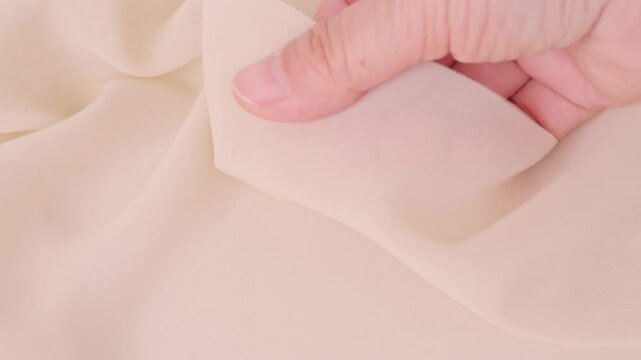 Female hands inspecting silk texture and quality delicate chiffon, crepe, hand feels sensual tactile pleasure, testing for durability, stretch and crease resistance