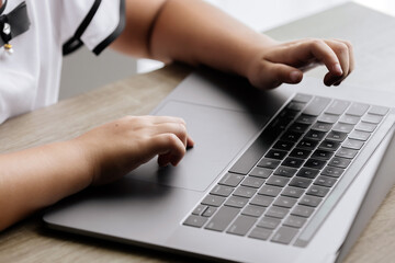 Close-up of children's hands typing on a laptop keyboard. Perfect for educational content, technology use by kids, or highlighting early learning in a digital age.