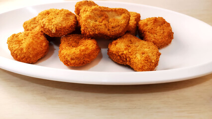 Chicken breast fillet in a crispy breading known as Nuggets on a white plate 
