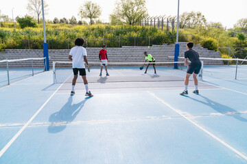 Group of players engaging in pickleball doubles match on outdoor court