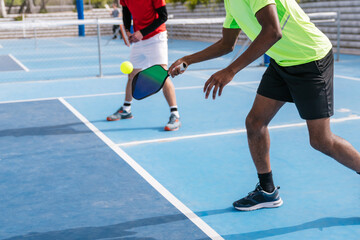 Close-up of multiracial pickleball players focused on hitting the ball