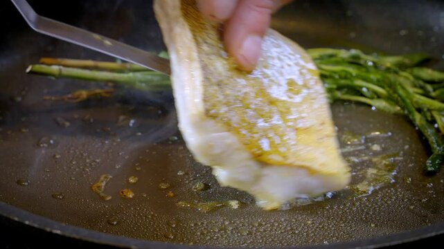 White fish pike-perch, zander are fried in a pan in hot olive oil. The cook flips the white fish fillet over to the other side. 4k slow motion 100 fps footage.