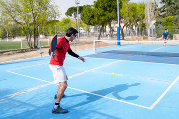 Pickleball player preparing to hit the ball on a blue court during a sunny day match