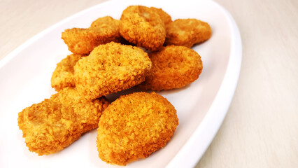 Chicken breast fillet in a crispy breading known as Nuggets on a white plate 
