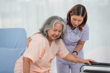 Obraz premium Smiling caring Asian doctor supporting holding hand of olde senior female patient at clinic or hospital