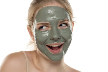 Beautiful young woman posing with a facial green mud mask on her face. Skin care and treatment, spa, natural beauty and cosmetology concept
