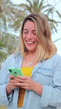 Vertical Slow motion fotage of one young adult woman walking and having fun using a cellphone social media application. feamale texting and sending messages on her smartphone. Lady holding phone