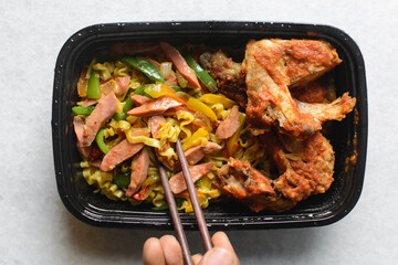 Overhead view of Singaporean noodles in a black disposable plate, top view of Singaporean fusion...