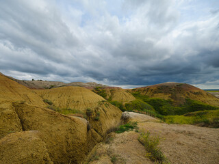 Colorful hues of yellow and green in the rolling hills of the Badlands of South Dakota as rain clouds move in