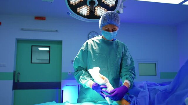 Doctor covers the operated hand of a patient with bandage. Finishing the surgery in modern hospital.