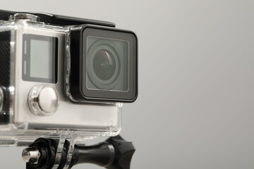 Fototapeta premium Modern action camera and mount on grey background, closeup. Space for text