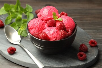 Delicious raspberry sorbet in bowl, fresh berries, mint and spoon on wooden table, closeup