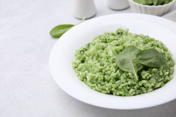 Delicious spinach risotto on light grey table, closeup