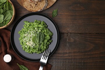 Delicious spinach risotto with parmesan cheese served on wooden table, flat lay. Space for text