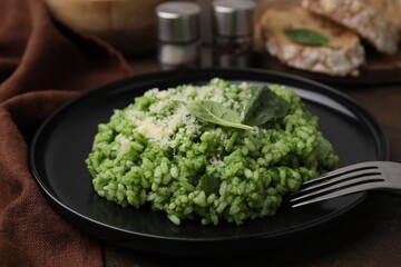 Delicious spinach risotto with parmesan cheese served on table, closeup