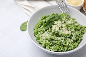Delicious spinach risotto with parmesan cheese served on white tiled table, closeup. Space for text