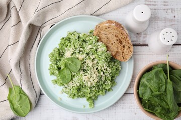 Tasty spinach risotto served with bread on white wooden table, flat lay