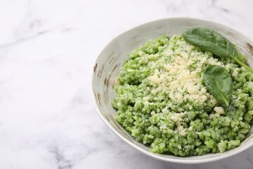 Tasty spinach risotto served on white marble table, closeup. Space for text
