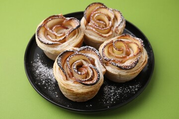 Freshly baked apple roses on green background, closeup