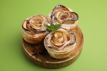 Freshly baked apple roses with mint on green background, closeup