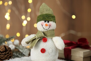 Cute decorative snowman and other Christmas decor on artificial snow, closeup