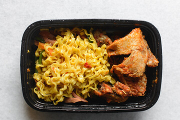 Overhead view of Singaporean noodles in a black disposable plate, top view of Singaporean fusion...