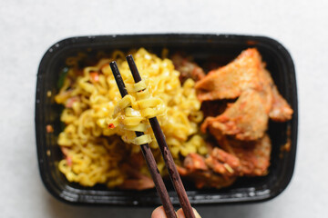 Overhead view of egg noodles noodles in wooden chopsticks, top view of Singaporean fusion noodles in chopsticks