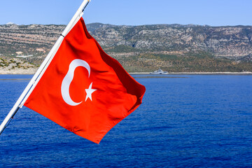 Red turkish flag waving over the Mediterranean sea