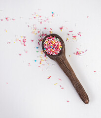 wooden spoon with sprinkles on white background