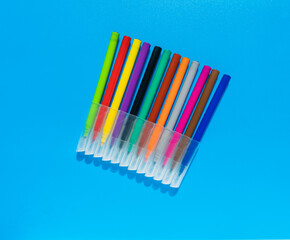 Colorful markers, felt-tip pen lie flat on blue background. Top view.