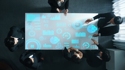 Top down aerial of collaborate professional diverse business people discuss marketing strategy with hologram of marketing data analysis graph, diagram or financial profit investment plan. Directorate.