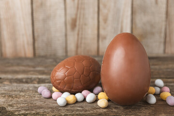 Easter chocolate egg on textured background. Easter celebration concept. Easter chocolate rabbit. Chocolate sweet eggs. Candies on textured wooden table. Space for text.Copy space. Gift. Banner.