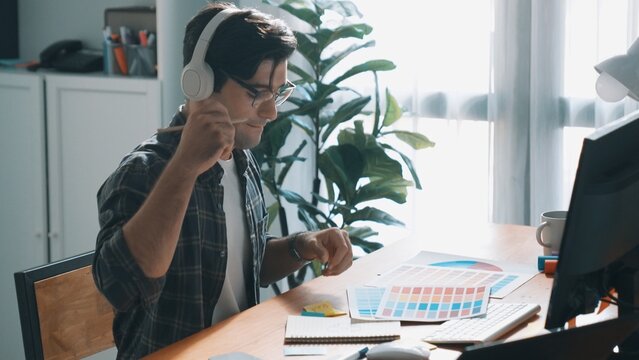 Top view of skilled interior design graphic while listen music from headphone. Professional project manager working while using headset and listening relaxed song and move along at studio. Symposium.