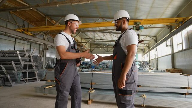 Multiracial engineers handshake success in metal profile warehouse