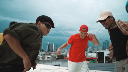 Caucasian hipster walking while dancing together at rooftop with city view. Multicultural dancer practicing street dance at cityscape or sky scrapper. Street dancing. Outdoor sport 2024. Hiphop.