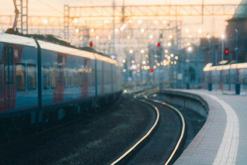 Fototapeta premium The train station in&nbsp;the evening. The rails bend and go&nbsp;off into the distance. The trains are on&nbsp;the railway track