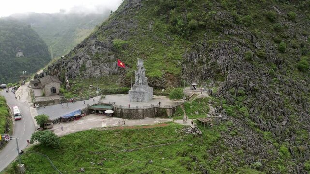 Aerial view of the youth monument surrounded by scenic mountains and a winding road, Meo Vac, Vietnam.