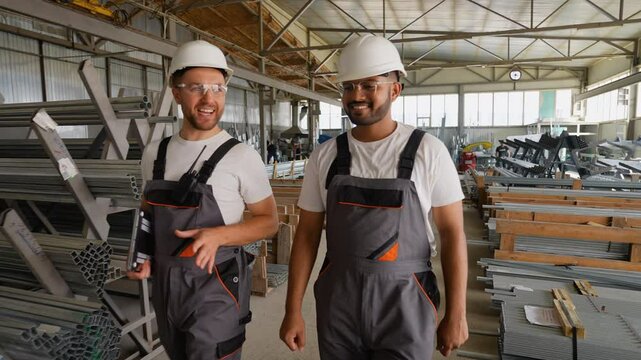 Caucasian foreman and Indian worker walking in metal profile warehouse