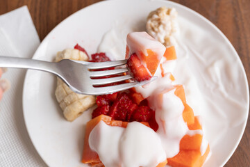 tenedor con fruta con yogurt y plato de desayuno