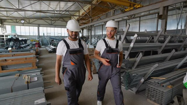 Two diverse workers walking in metal profile warehouse