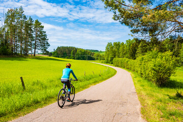 Woman cyclist riding bicycle on gravel forest road, Wigry National Park, Podlasie, Poland