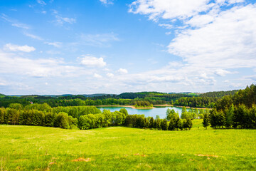 View of Jaczno lake from hill with green meadow and trees, Suwalski Landscape Park, Podlasie, Poland