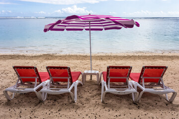 Parasol et transats rouges sur plage de l’Hermitage, île de la Réunion 