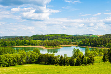 Obraz premium View of Jaczno lake from hill with green meadow and trees, Suwalski Landscape Park, Podlasie, Poland